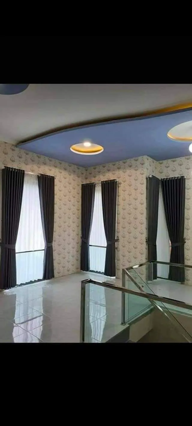 Gorden polos abu-abu tua dengan vitrase putih dipasang di ruangan berwallpaper motif, sehingga ruangan tetap terlihat seimbang